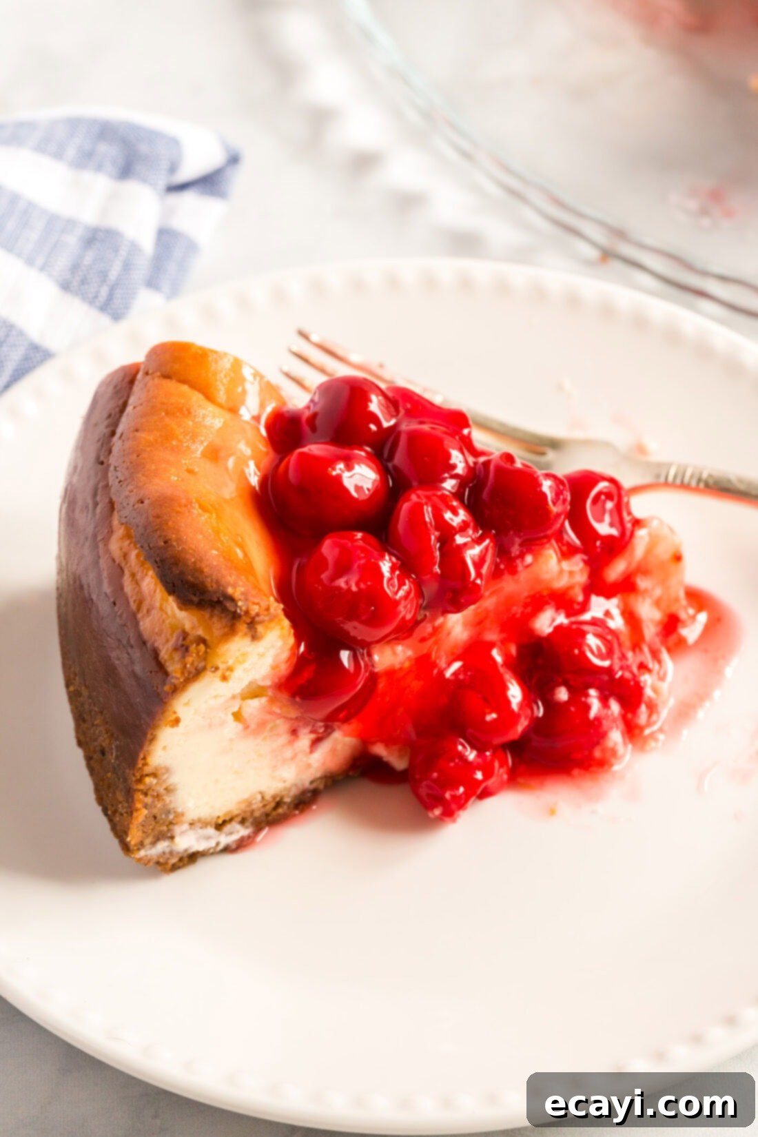 Decadent Cherry Cheesecake 2 A perfectly sliced piece of cherry cheesecake on a white plate, showcasing its creamy texture and vibrant cherry topping.