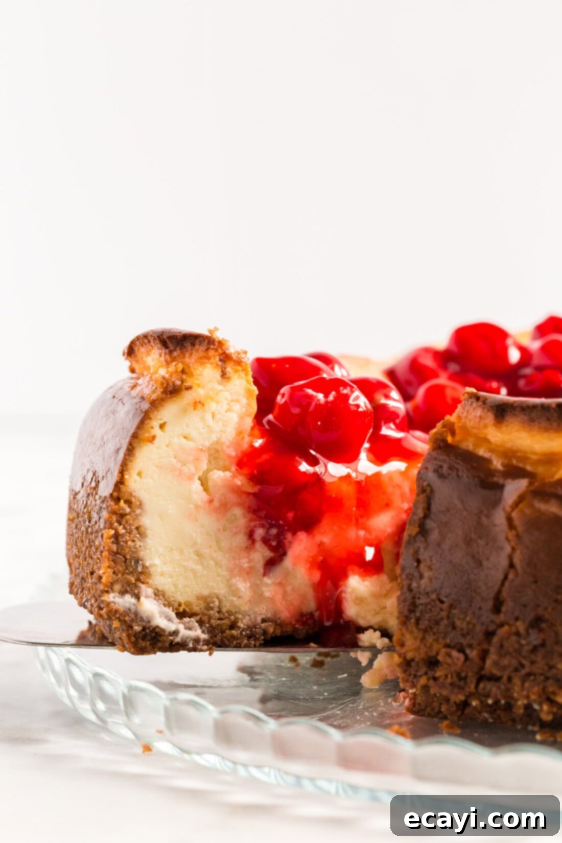 Decadent Cherry Cheesecake 10 A slice of cherry cheesecake being carefully lifted from the whole cake with a spatula, highlighting its perfect form and topping.