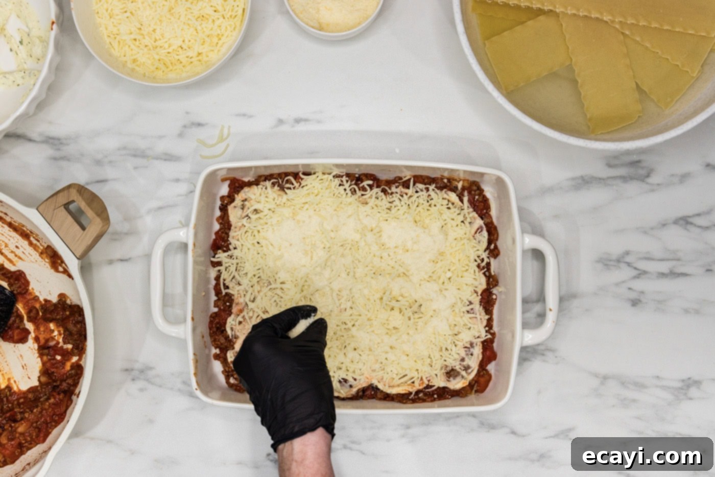 Classic Italian Lasagna 12 A hand gently sprinkling shredded mozzarella and grated Parmesan cheese over the ricotta layer, adding a cheesy finish to the lasagna layers.