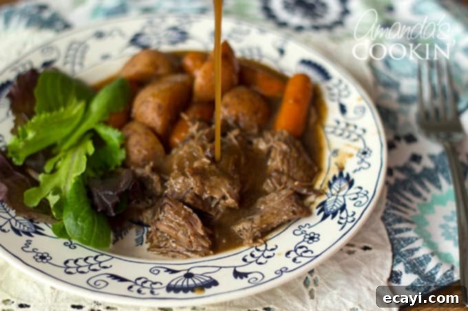 I have been making this crockpot roast beef for many, many years. This roast only needs a few ingredients and cooks all day in your slow cooker to perfection. #crockpotroast #crockpotroastbeef #slowcookerroast #crockpotpotroast #crockpotdinners #crockpotrecipes #slowcookerrecipes #chuckroast #weeknightdinners  Gravy pouring onto crockpot roast beef and carrots from an older version of the recipe