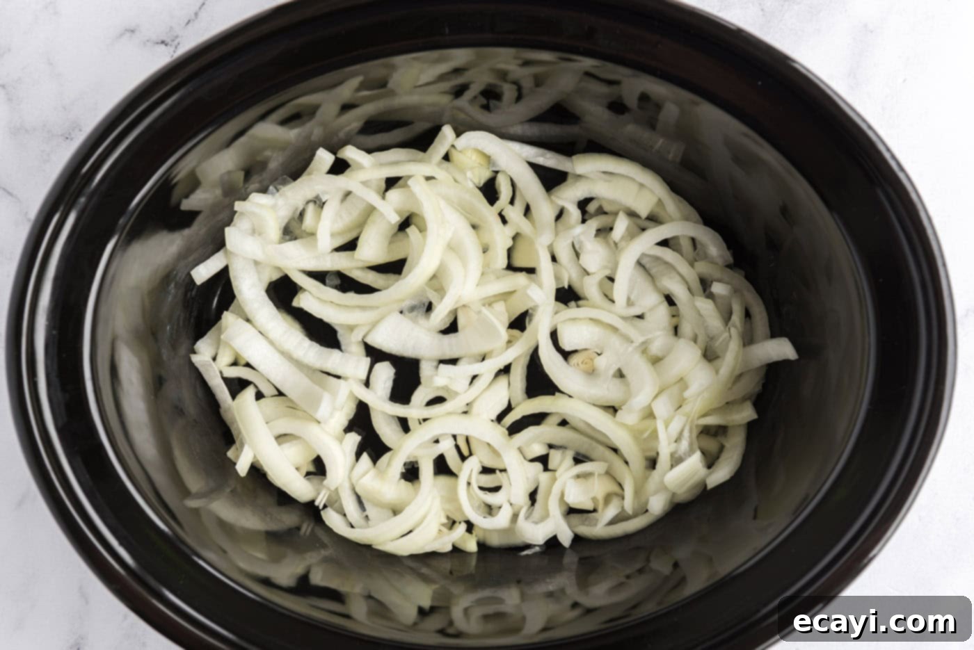 Melt-in-Your-Mouth Slow Cooker Pot Roast 5 Sliced onions covering the bottom of a slow cooker crock