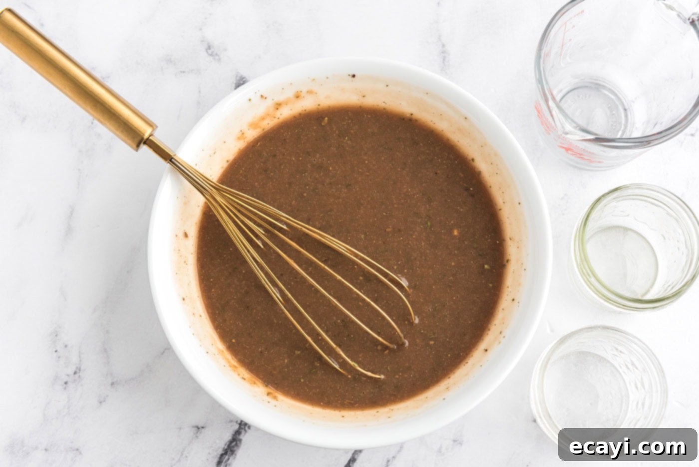 Melt-in-Your-Mouth Slow Cooker Pot Roast 9 Gravy mixture in a bowl with a whisk, ready to be poured