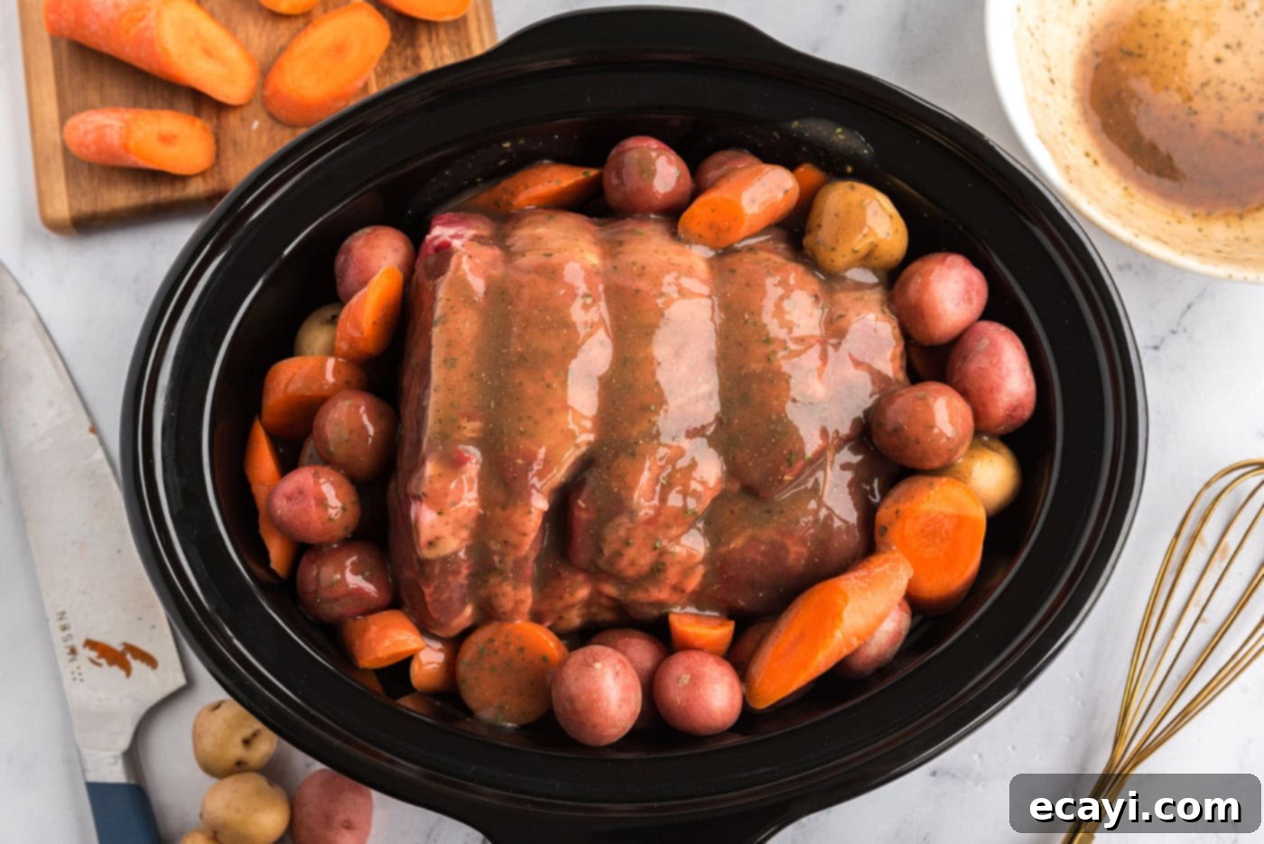 Melt-in-Your-Mouth Slow Cooker Pot Roast 10 Gravy mixture being poured over the crockpot roast beef and vegetables