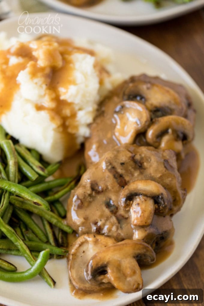 Savor the taste of homemade Salisbury Steaks – a comforting and easy ground beef dinner that can be made in a slow cooker, oven, or skillet. Perfect for family meals! Salisbury steak on a plate with mashed potatoes and green beans, a classic comfort food meal.