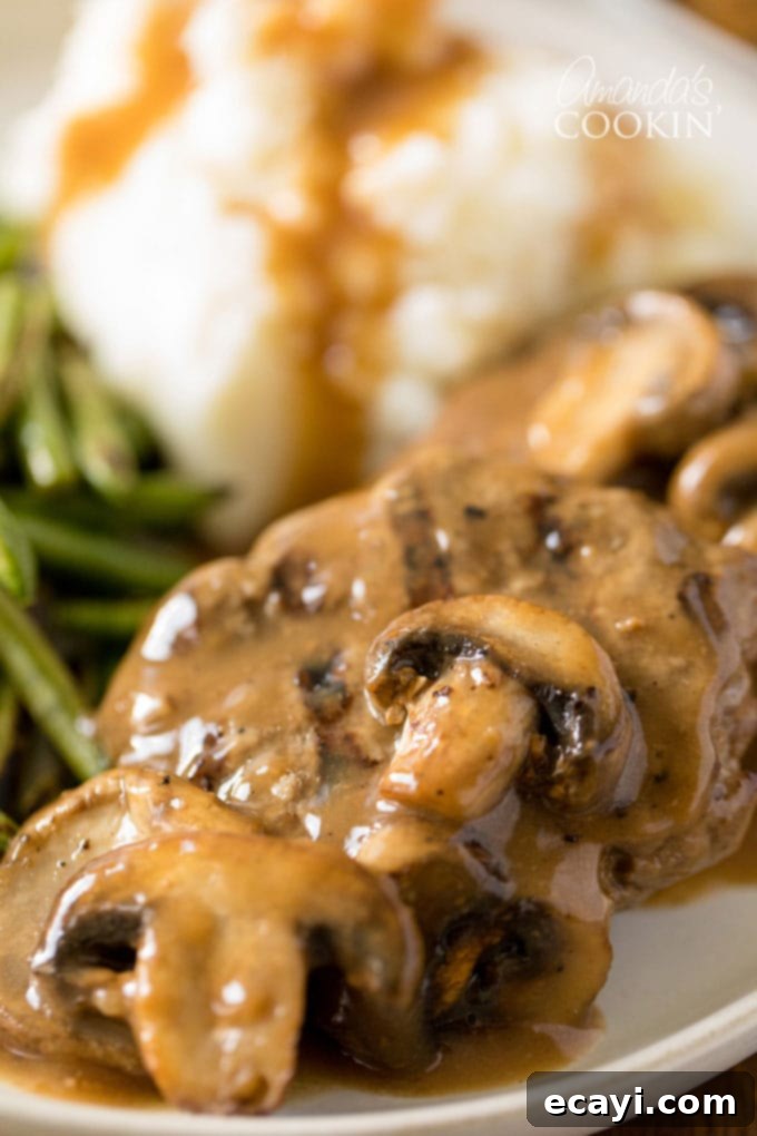 Homestyle Salisbury Steaks 2 Juicy Salisbury steaks covered in rich brown gravy with sliced mushrooms, ready to be served as a hearty dinner.