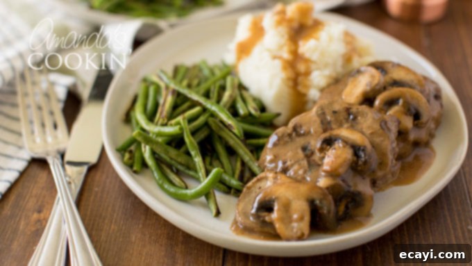 Homemade Salisbury Steaks are a fantastic ground beef dinner idea, perfect for the slow cooker, oven, or skillet. Two Salisbury steaks with gravy on a dinner plate, showcasing a delicious homemade meal.