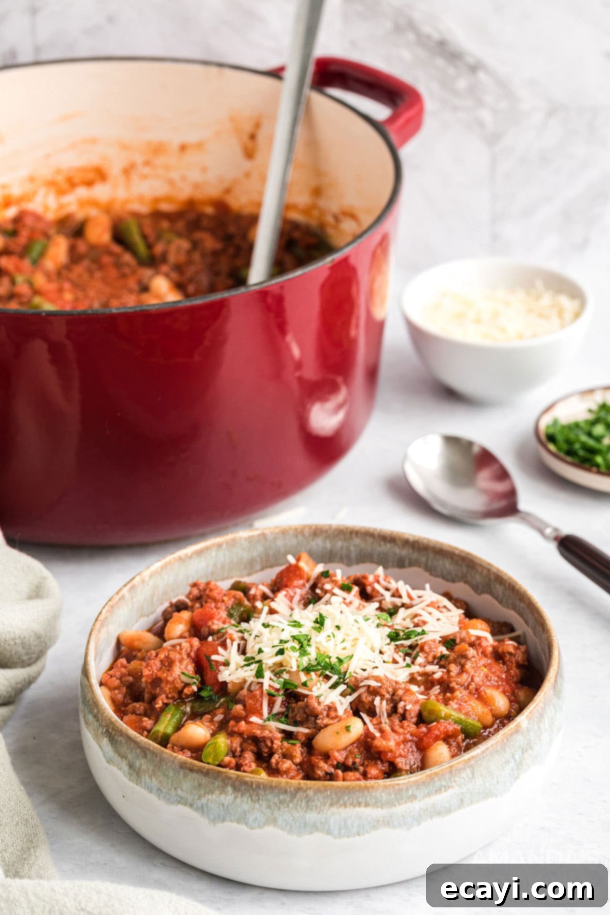 Hearty Italian Hamburger Stew: Simple, Delicious, and Comforting with Warm Bread A steaming bowl of hearty Italian hamburger stew, garnished with fresh parsley and a side of warm crusty bread, with a Dutch oven blurred in the background.