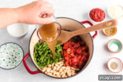 Hearty Ground Beef & Vegetable Stew 8 pouring vegetable broth and other ingredients into pot