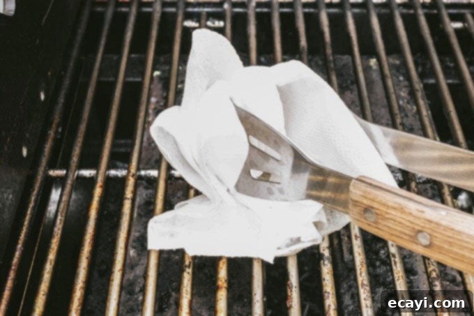 Chargrilled Salmon Bliss 8 tongs holding paper towel over grill grates