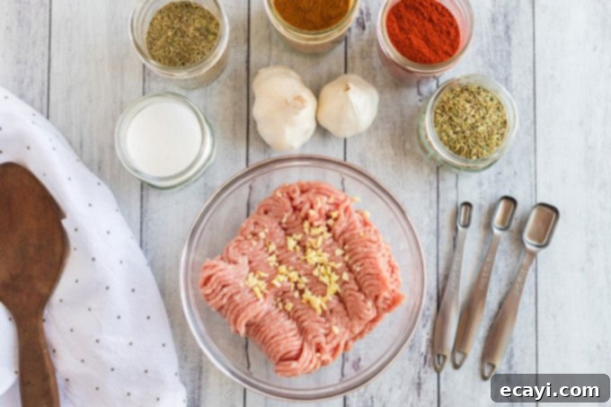 Crafting Authentic Pizza Sausage 4 A selection of fresh ingredients for homemade pizza sausage laid out on a wooden cutting board: lean ground pork, whole garlic cloves, and various dried herbs and spices.