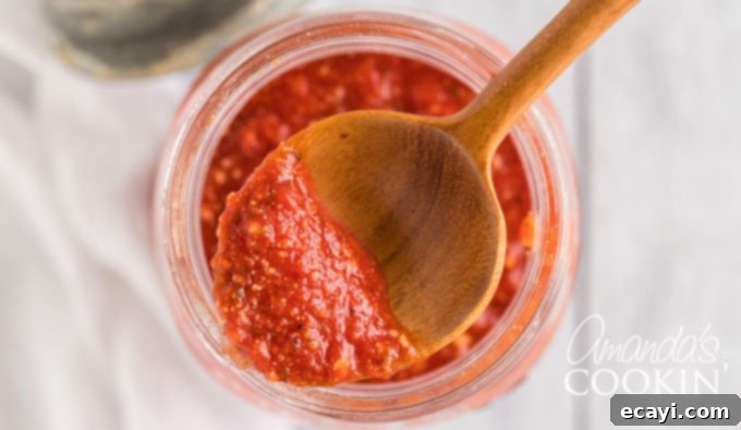How to make homemade pizza sauce. You likely have all the ingredients in your pantry! Learn how to make your own pizza sauce and freeze it for later too! close up of spoon with sauce