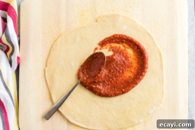 Pizza's Flavor Foundation 6 spreading sauce on pizza dough