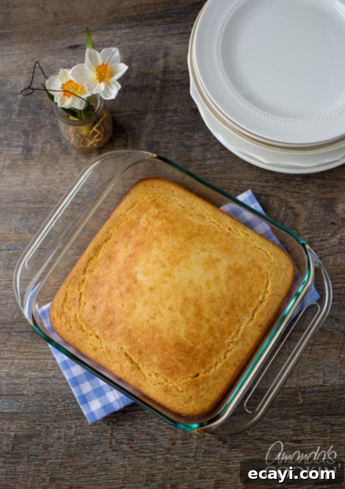 Honey-Kissed Cornbread 3 A golden-brown pan of sweet cornbread cooling on a blue checkered towel