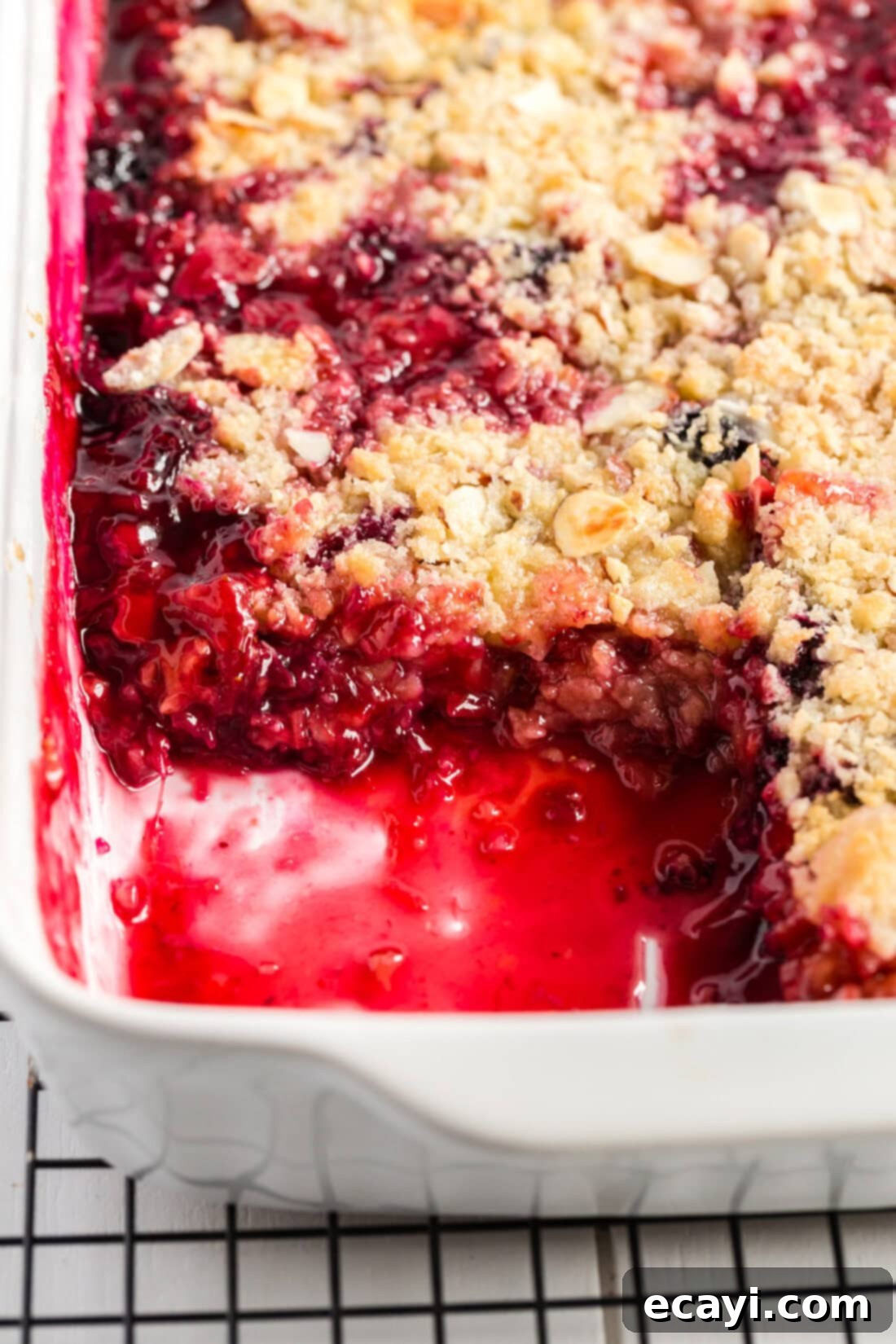 Blue Ribbon Rhubarb Delight 4 Baking dish of Prize Winning Berry Rhubarb Crumble with a serving removed, showcasing the fruit and topping.