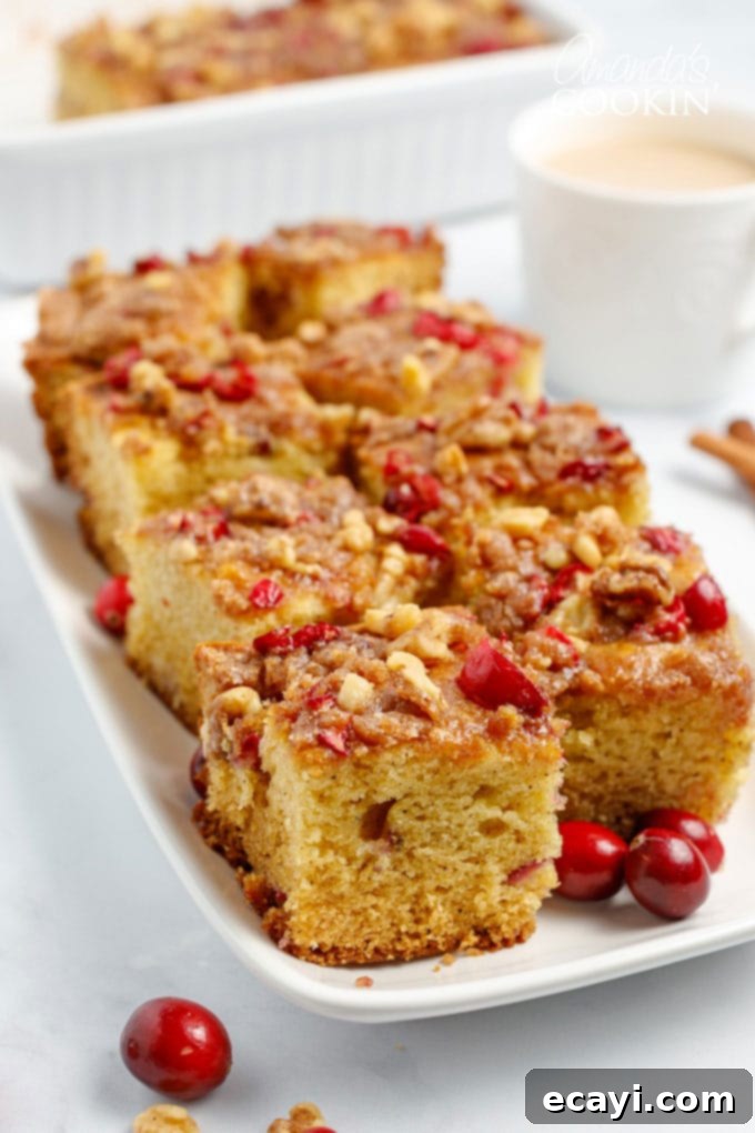 Cranberry Coffee Cake is filled with plump cranberries and topped with a delicious streusel topping. This is an easy to make coffee cake for Christmas. Squares of delicious Cranberry Coffee Cake on a white plate, ready to be served.