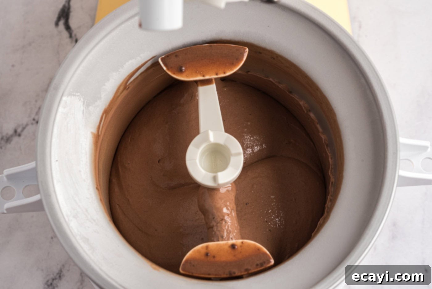 Decadent Homemade Chocolate Ice Cream 15 Churning the chocolate ice cream mixture in a home ice cream maker, showing the thickening process