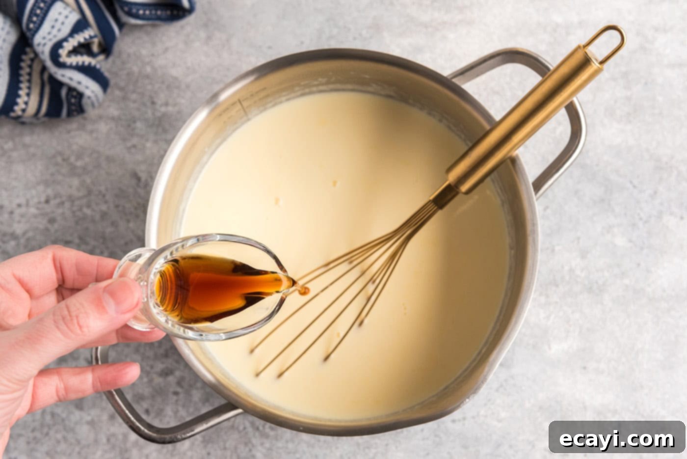The Ultimate Homemade Vanilla Ice Cream 9 pouring vanilla into bowl of egg and milk mixture