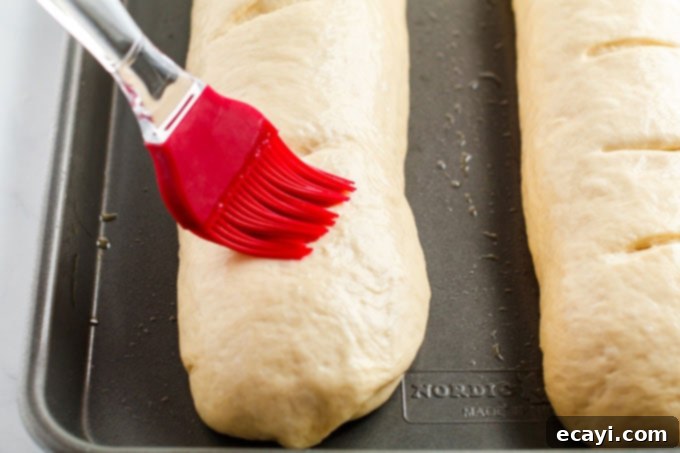Rustic Italian Loaf 12 brushing top of bread loaves