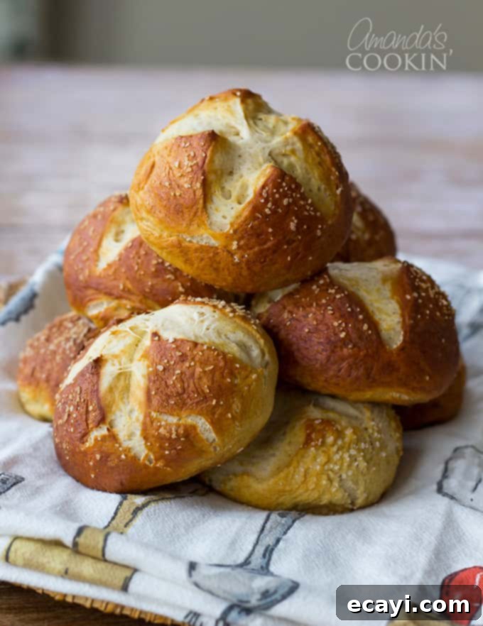 Pretzel Rolls 3 A stack of freshly baked bretzel rolls resting on a kitchen towel, showcasing their perfect shape and golden color.