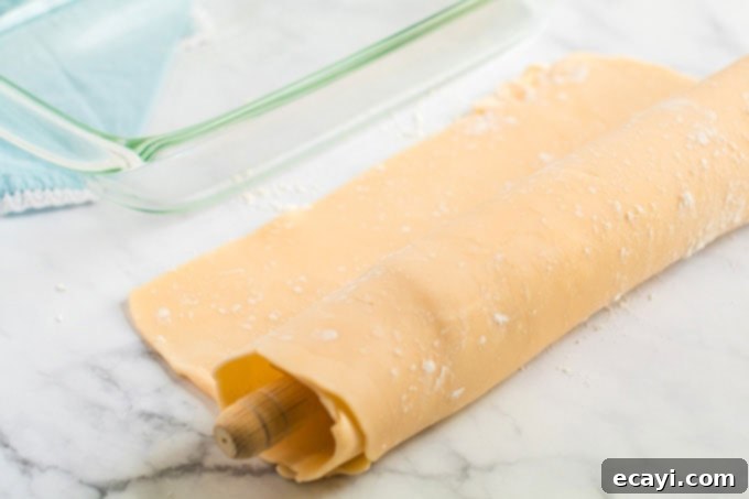 Heavenly Deep Dish Peach Pie 9 rolled pie crust dough draped over a rolling pin, ready to be transferred to the baking pan