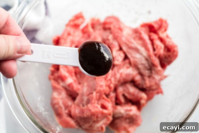 Khan's Caramel Beef 6 adding hoisin sauce to beef marinating in a bowl, showing a close-up of the process