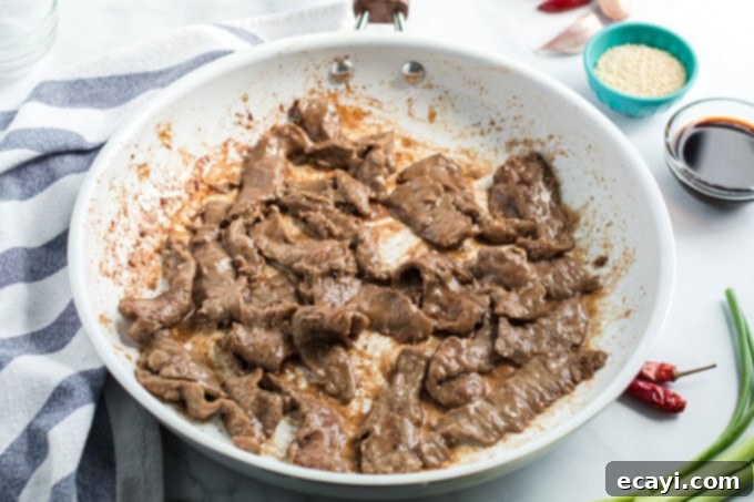 Khan's Caramel Beef 7 thinly sliced beef cooking in a hot skillet, showing the browning process