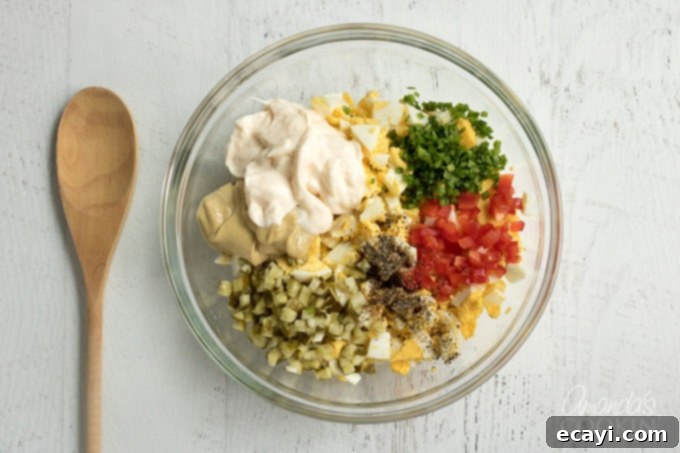 Combine all egg salad ingredients and mix to coat. A perfect dish for a potluck or BBQ! Step-by-step: Combining all egg salad ingredients in a bowl and mixing gently to coat evenly.