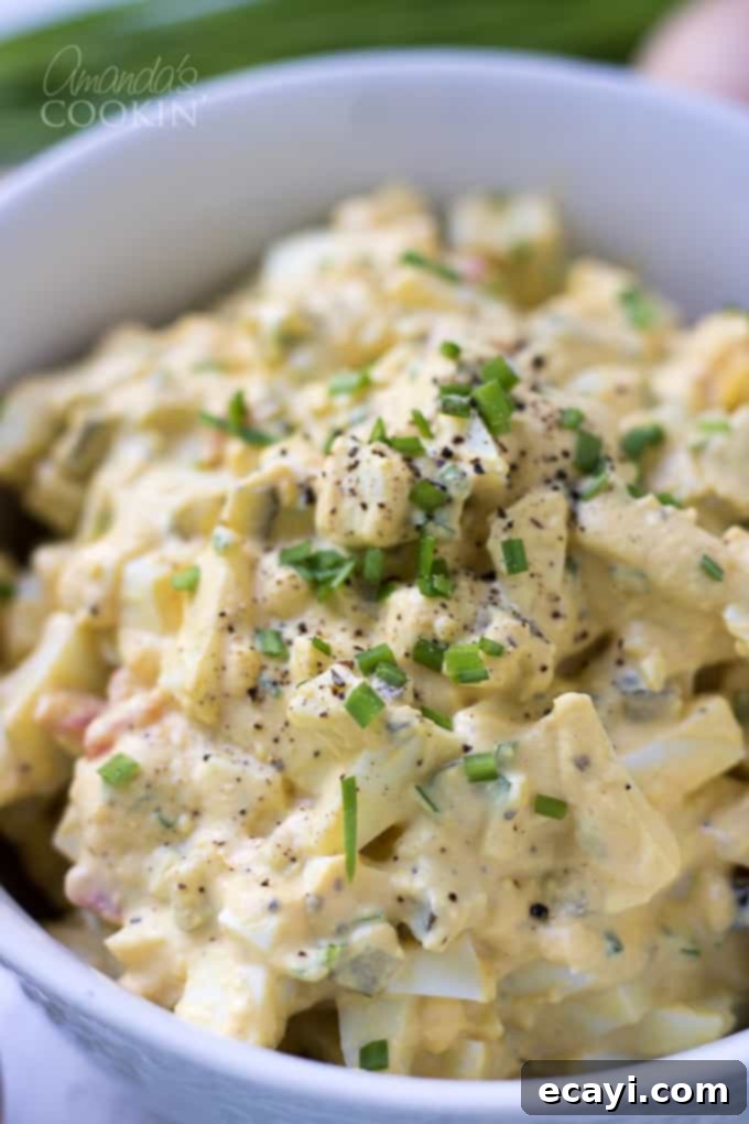 This Egg Salad is made up of all the classic ingredients from your traditional egg salad recipe. This is a great recipe for a potluck or BBQ! #easter #easterrecipes #eggsalad #BBQ #potluck #summer #summerrecipes #appetizers #lunch Finished egg salad, garnished with fresh chives and a sprinkle of black pepper, ready for serving.