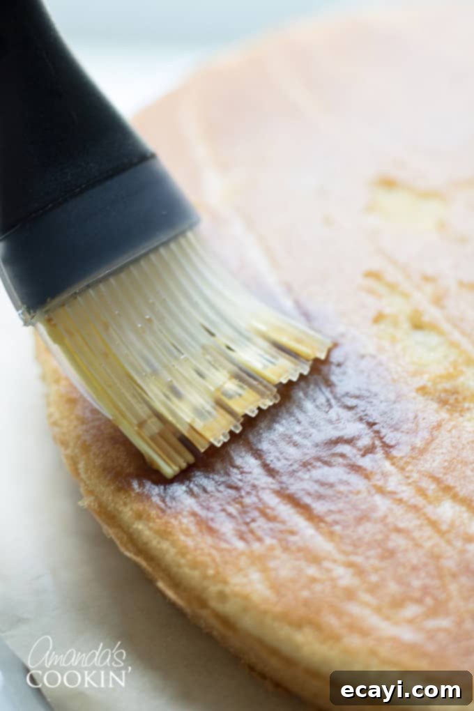Decadent Tiramisu 7 A pastry brush applying espresso syrup to a baked cake layer, infusing it with flavor.