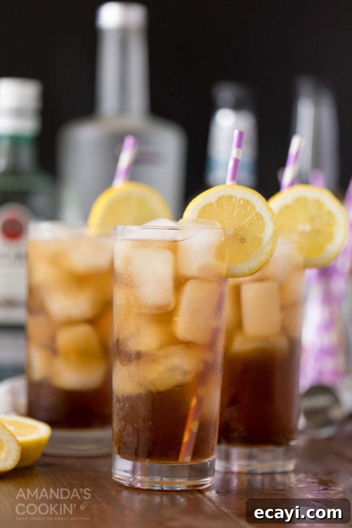 No Tea, All Buzz 6 Three tall glasses of Long Island Iced Tea, garnished with lemon slices, standing on a bar surface, ready for serving.
