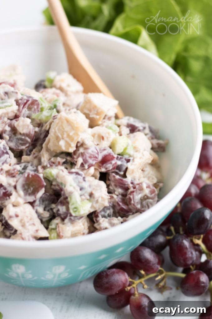 Creamy chicken salad with grapes, perfect for summer potlucks and BBQs. Large bowl of creamy chicken salad with red grapes, celery, and green onion, ready to be served