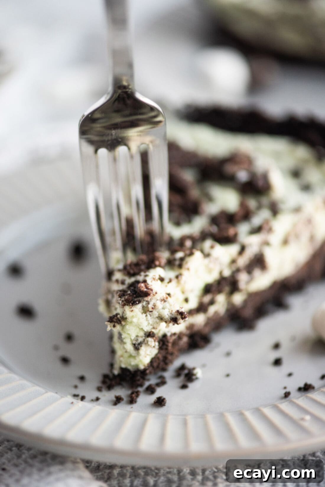 Decadent Grasshopper Pie 2 A fork taking a delicious bite out of a perfectly set slice of vibrant green Grasshopper Pie, showing its creamy texture and chocolate crust.