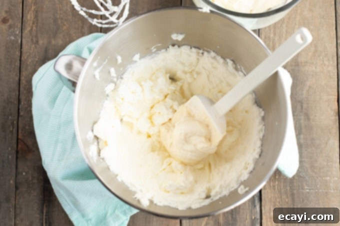 Timeless White Cake 8 Folding frosting ingredients together in a bowl with a rubber spatula