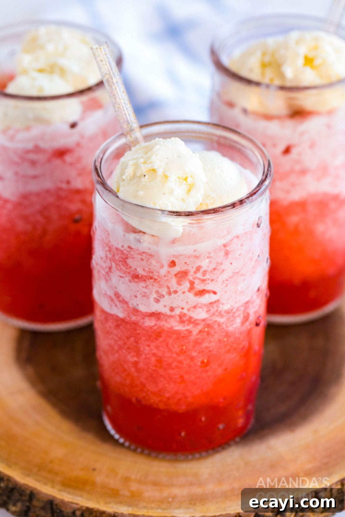 Easy Homemade Slushie Floats with Vanilla Ice Cream - Perfect for Summer Refreshment Two red slushie floats topped with vanilla ice cream and whipped cream, garnished with cherries and colorful straws, placed on a wooden surface.