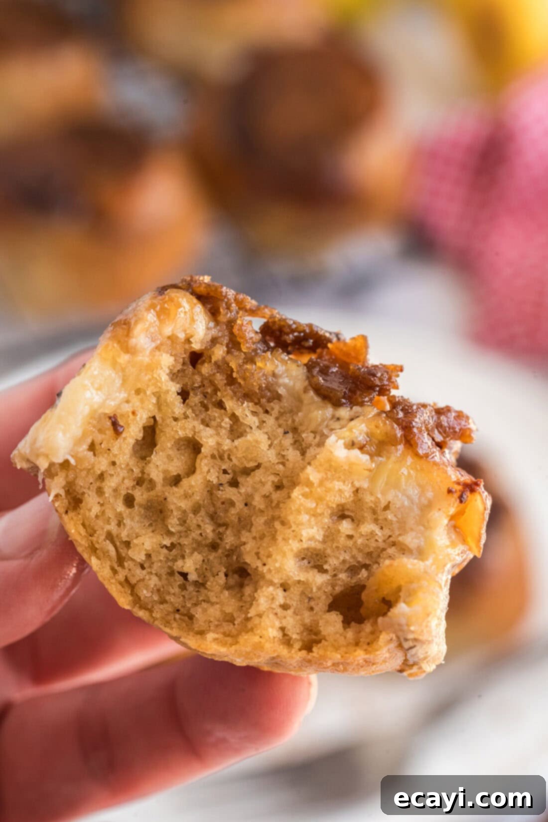 Sticky-Sweet Banana Crown Muffins 16 Hand holding up a Banana Upside Down Muffin with two bites taken out