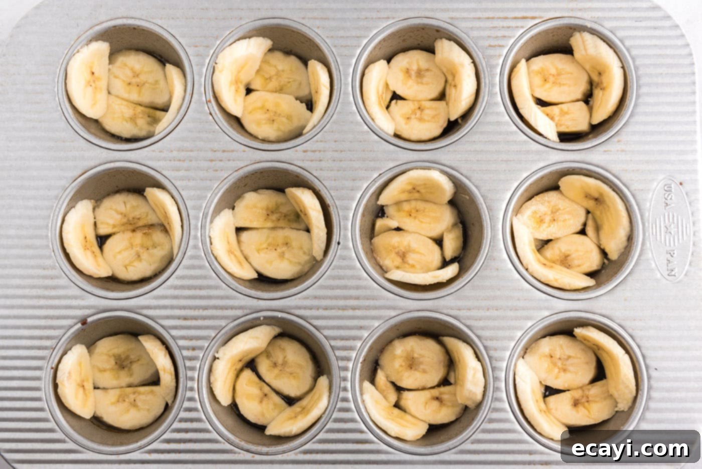 Sticky-Sweet Banana Crown Muffins 7 banana slices arranged in a muffin pan over caramelized sugar