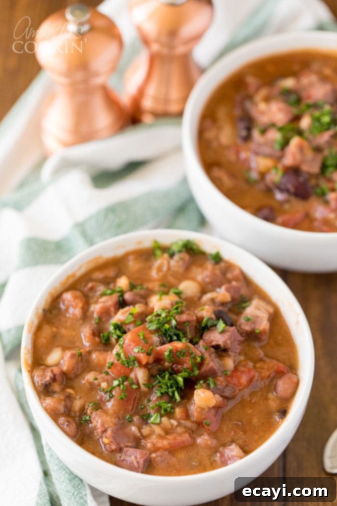 Hearty & Easy Ham and Bean Soup: The Ultimate Leftover Ham Recipe Two bowls of steaming ham and bean soup, garnished with fresh parsley, on a rustic wooden table.