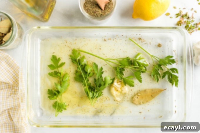 Prepare your lemon herb marinade with fresh ingredients for a burst of flavor in your grilled pork chops. Close-up shot of marinade ingredients (lemon, olive oil, herbs, garlic) mixed in a glass baking dish, ready for pork.