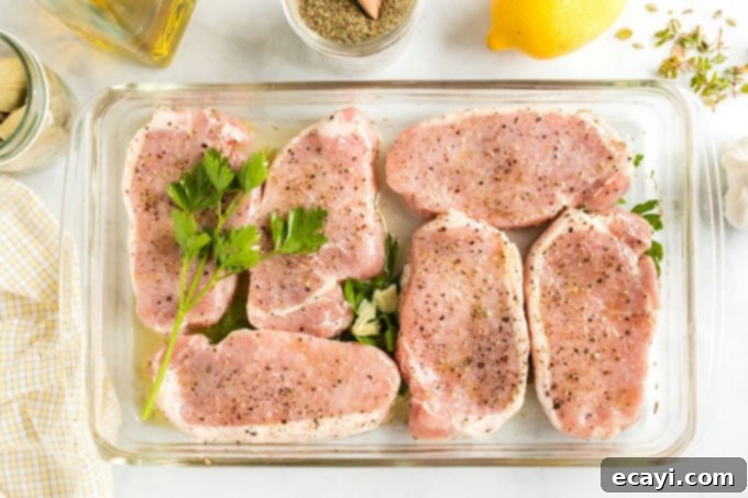 Let your pork chops soak up all the zesty lemon and aromatic herb flavors in this easy marinade for ultimate taste. Pork chops submerged in the golden lemon herb marinade within a glass dish, absorbing all the delicious flavors.