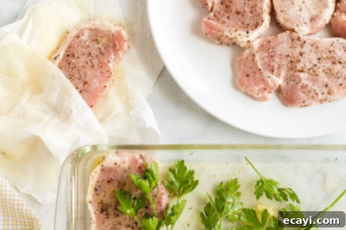 Ensure your pork chops are perfectly dry before grilling to get that beautiful, crispy sear. Hands patting down pork chops with paper towels, a critical step before grilling to ensure a perfect sear.