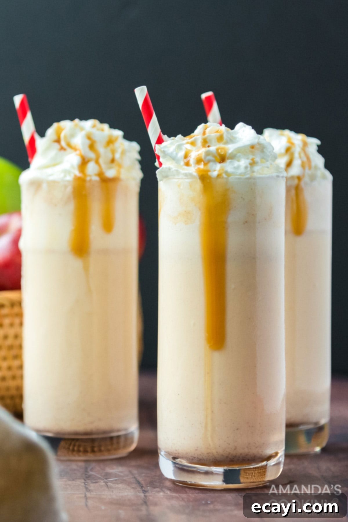 Only 3 ingredients for this delicious, fall inspired apple cider milkshake. So easy to make and an amazing way to wrap up summer. Three apple cider milkshakes in tall glasses, with garnishes and a fall background
