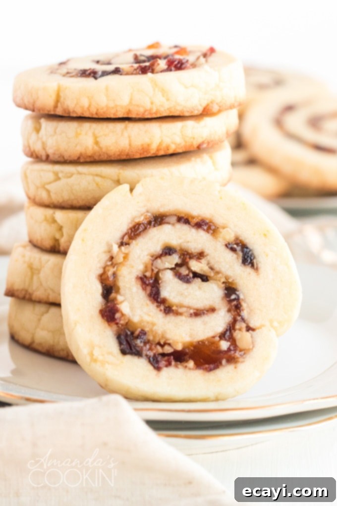 Cranberries, pecans, and orange marmalade are used as a filling and the dough is rolled up jelly-roll style to make these Cranberry Orange Spiral Cookies. A stack of golden brown cranberry orange spiral cookies, revealing the beautiful filling inside.