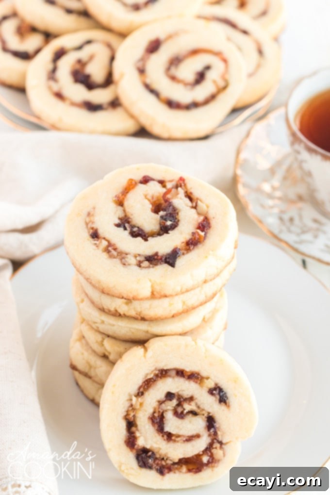 Cranberries, pecans, and orange marmalade are used as a filling and the dough is rolled up jelly-roll style to make these Cranberry Orange Spiral Cookies. Beautifully baked cranberry orange spiral cookies arranged on a cooling rack, ready to be enjoyed.