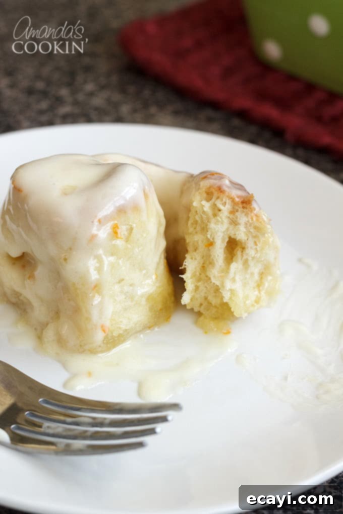You'll love these orange rolls just as much as homemade cinnamon rolls. This quick orange rolls recipe is ideal for those who prefer homemade over canned. #orangerolls #cinnamonrolls #breakfastrolls #orange #creamcheese #creamcheesefrosting #sweetrolls #orangerollsrecipe #breakfast #sweetrollrecipe one orange roll on plate