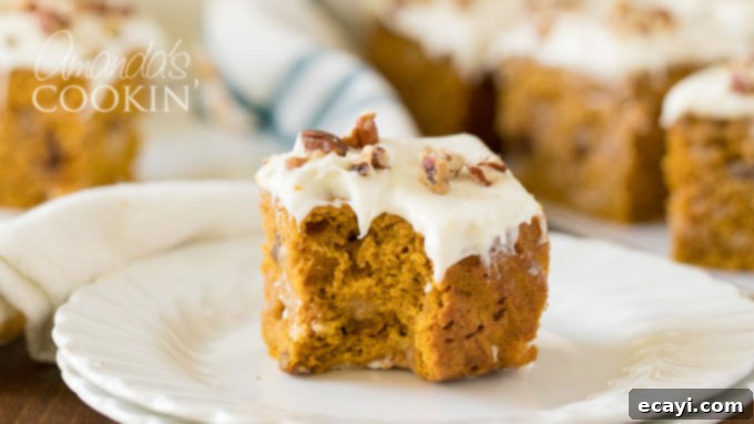 Bite-sized Pumpkin Cake with White Chocolate and Pecans Close-up of a piece of pumpkin cake with a bite taken out, showing the texture