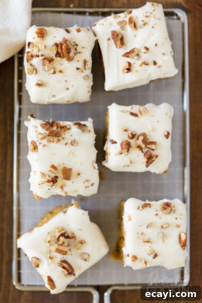 Homemade Pumpkin Cake with White Chocolate and Pecan Topping Six perfectly frosted pumpkin cake squares arranged on parchment paper