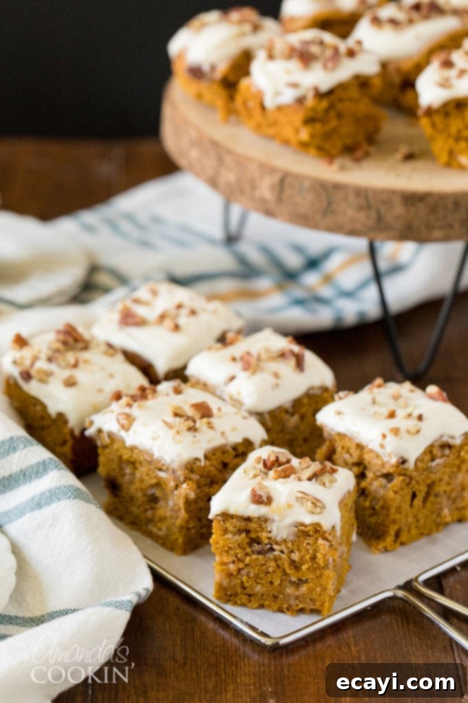 Moist Pumpkin Cake with White Chocolate Frosting, Ready to Serve Squares of frosted pumpkin cake with a full plate of cake in the background