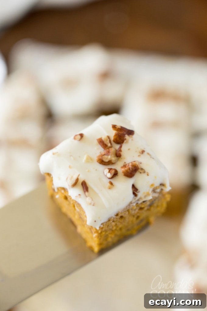Perfectly Cut Square of Pumpkin Cake with Cream Cheese Frosting A single slice of moist pumpkin cake on a spatula, showcasing the frosting and mix-ins