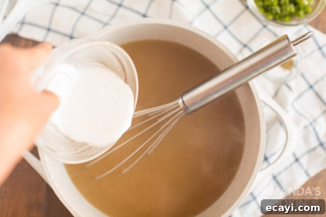 Golden Egg Flower Soup 3 adding cornstarch slurry to boiling chicken broth for homemade egg drop soup