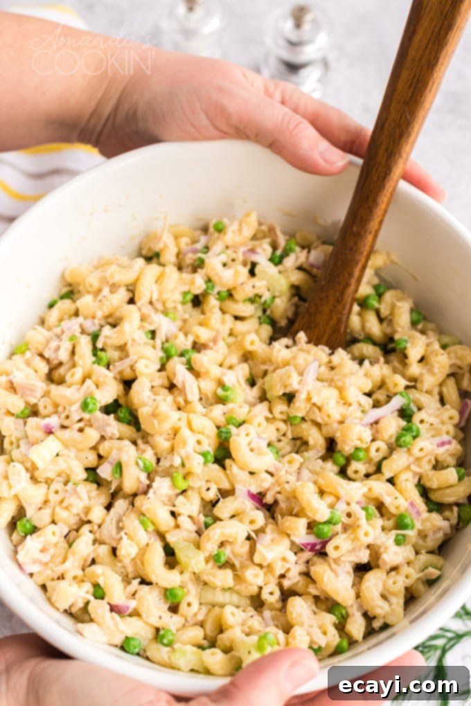 This recipe for tuna pasta salad is easy to make and is perfect for potlucks and barbecues, or just a protein packed lunch! someone holding a big bowl of tuna pasta salad, showing its generous serving size